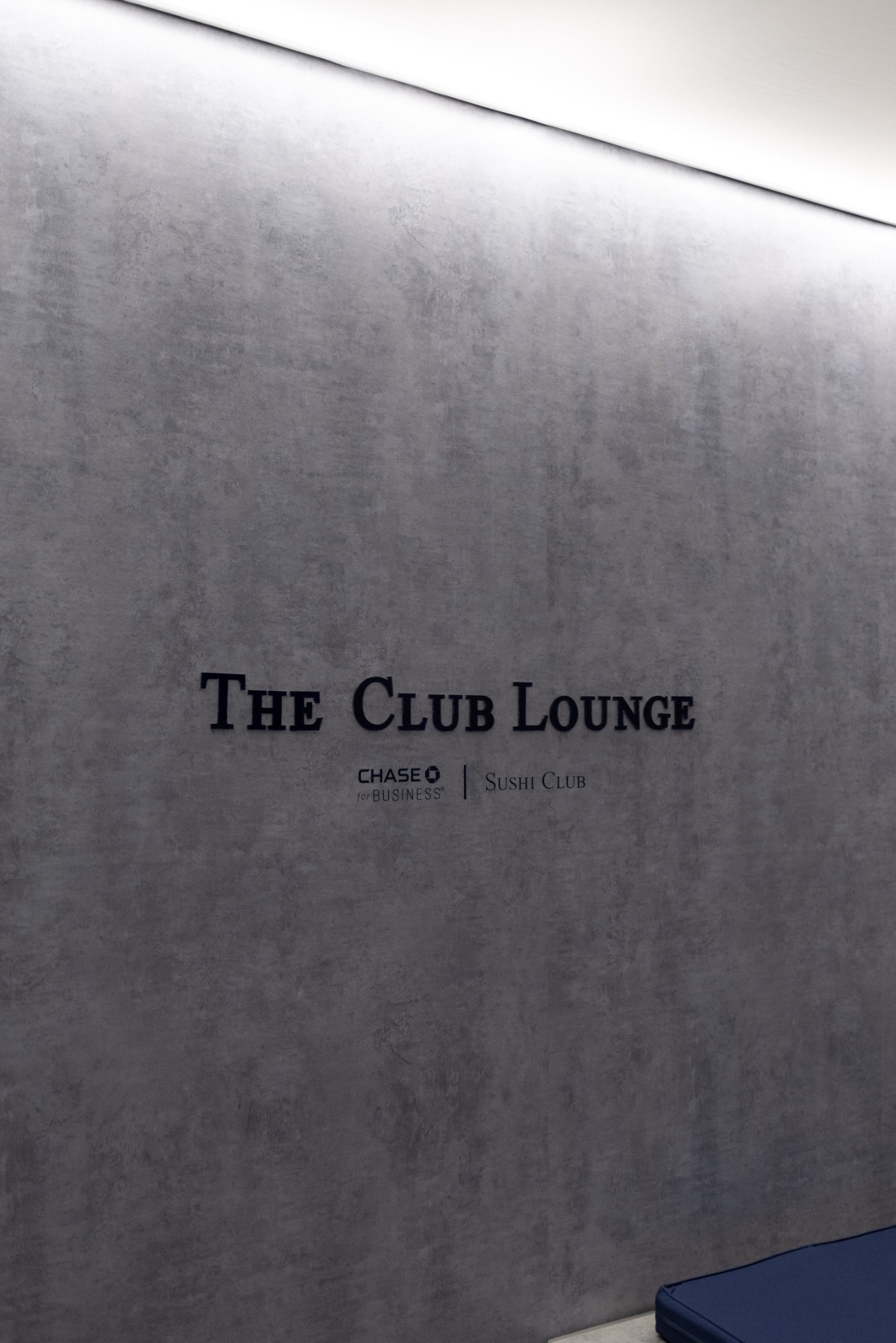 The Club Lounge sign with Chase for Business and Sushi Club logos on a concrete-textured wall
