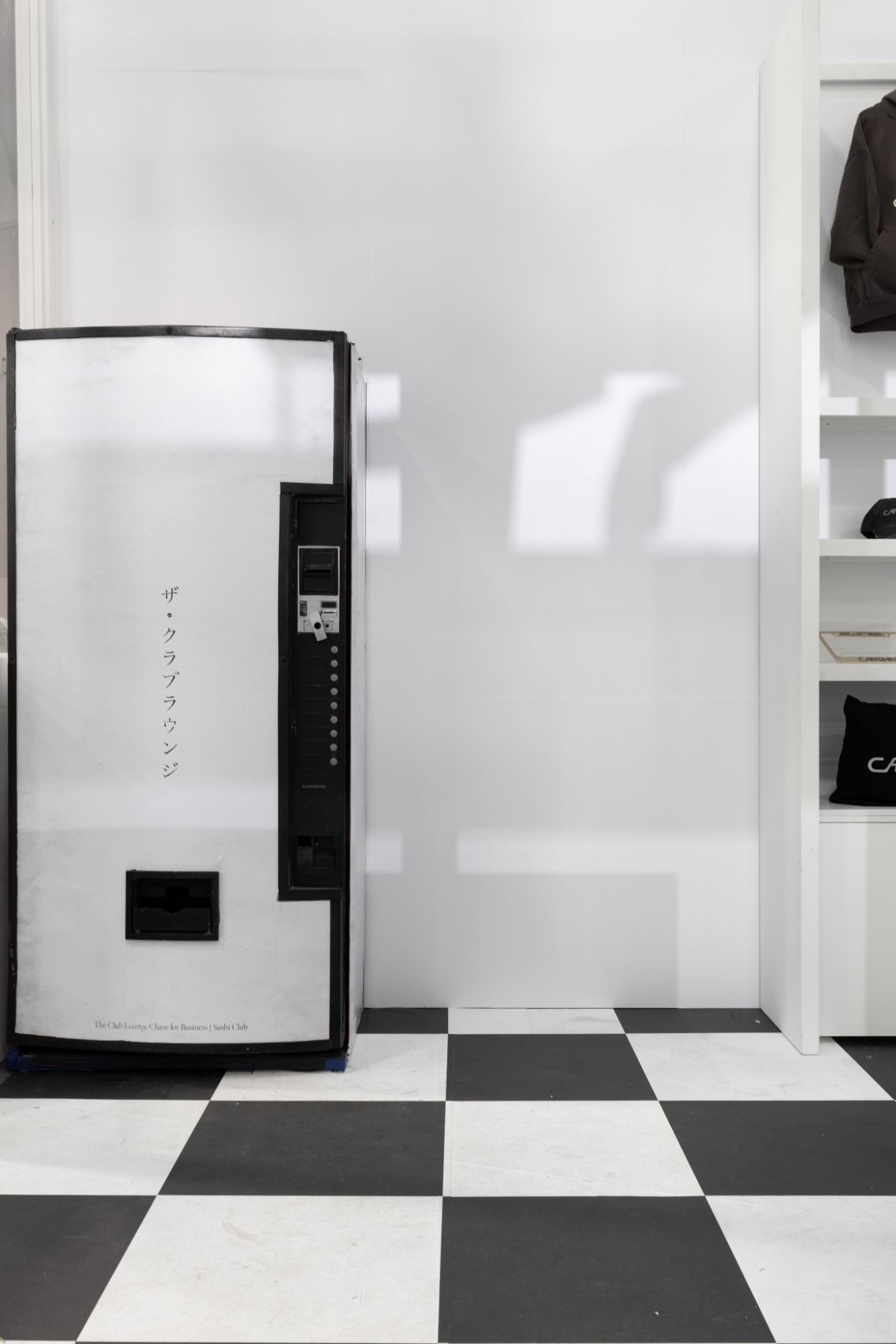 The closed vending machine marked The Club Lounge in Japanese, on a black-and-white checkered floor