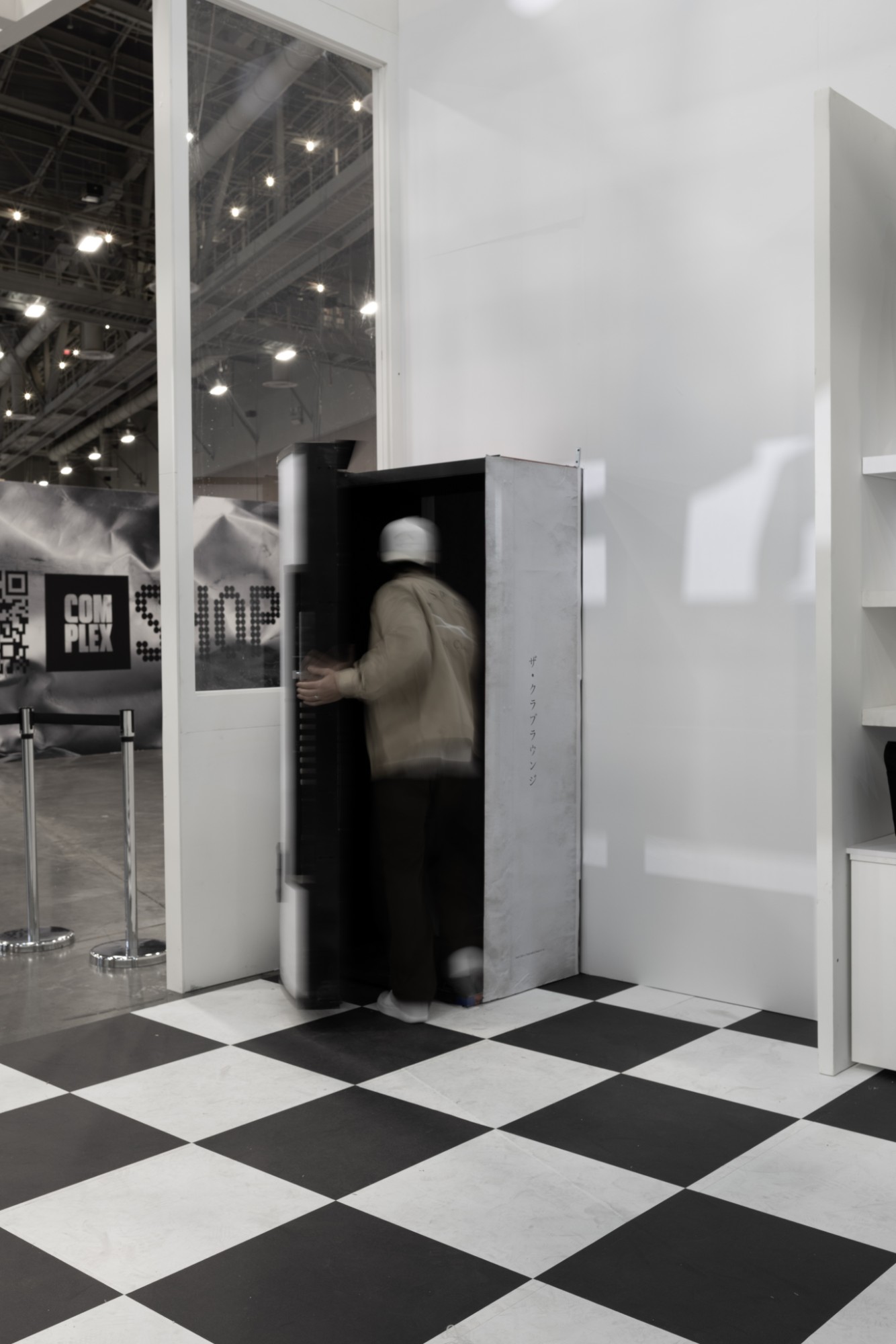 A guest opens the vending-machine door to the Club Lounge, with the ComplexCon show floor behind the glass